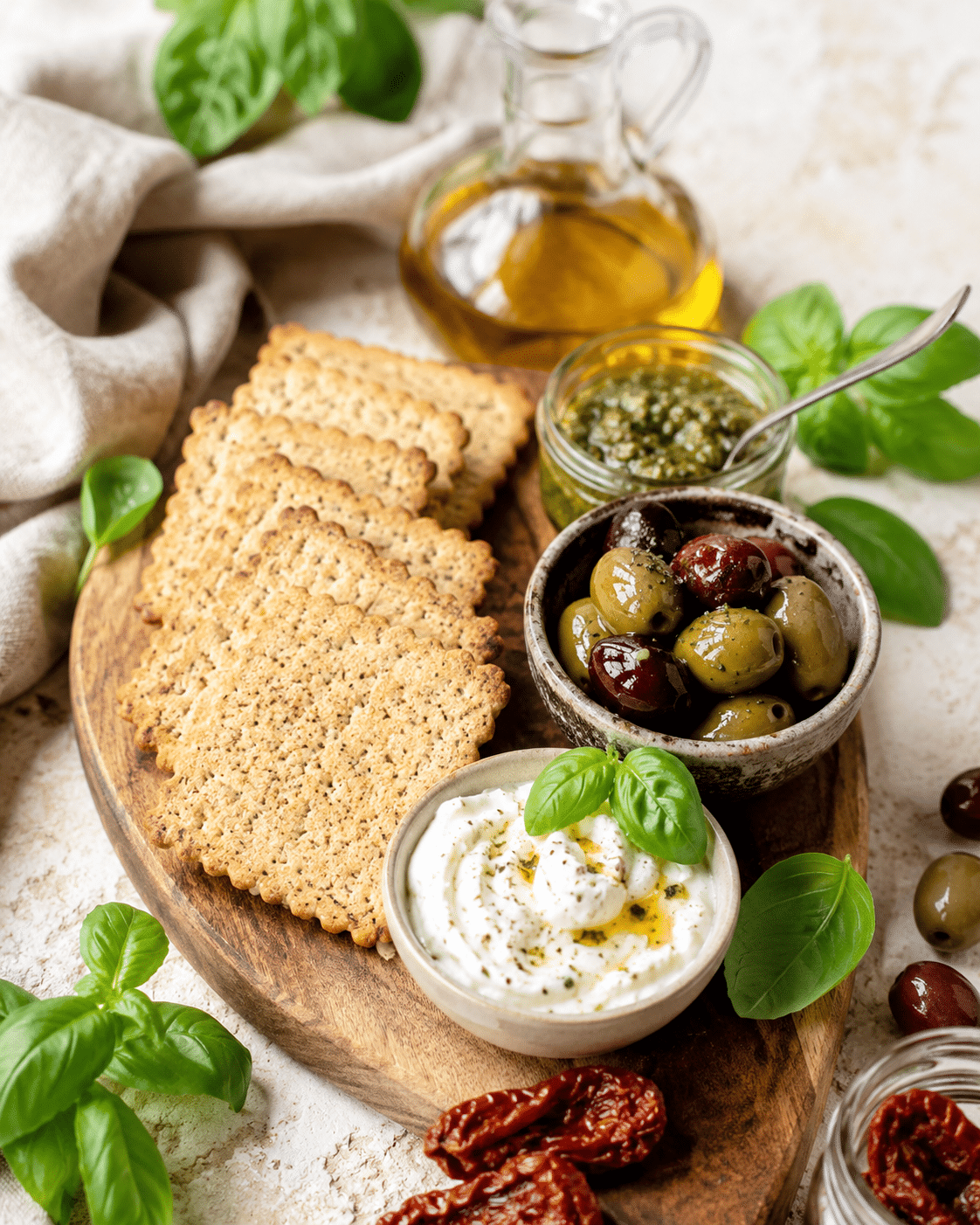 Aperitivos sin gluten con crackers italianos, queso, pesto, aceitunas y tomates secos.